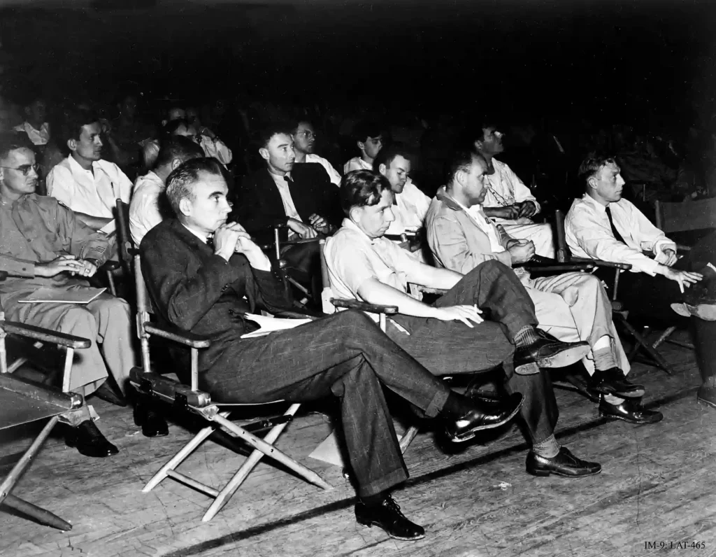 En la primera fila están Norris Bradbury, John Manley, Enrico Fermi y J. M. B. Kellogg. Robert Oppenheimer, con abrigo oscuro, está detrás de Manley; a la izquierda de Oppenheimer está Richard Feynman. El oficial del ejército a la izquierda es el coronel Oliver Haywood. Crédito: Wikimedia Commons